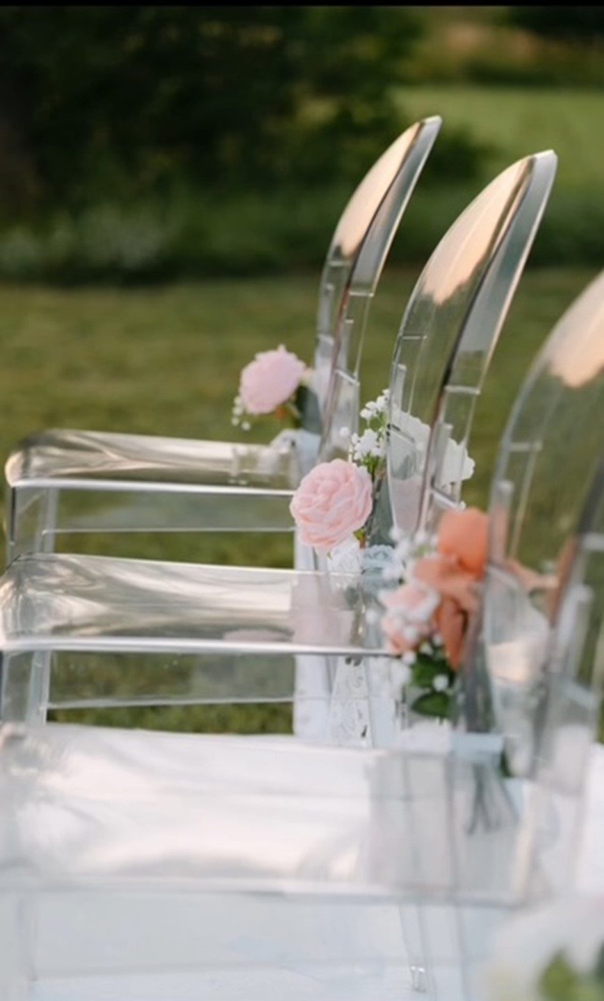 Transparante stoelen met bloemdecoratie bij ceremonie